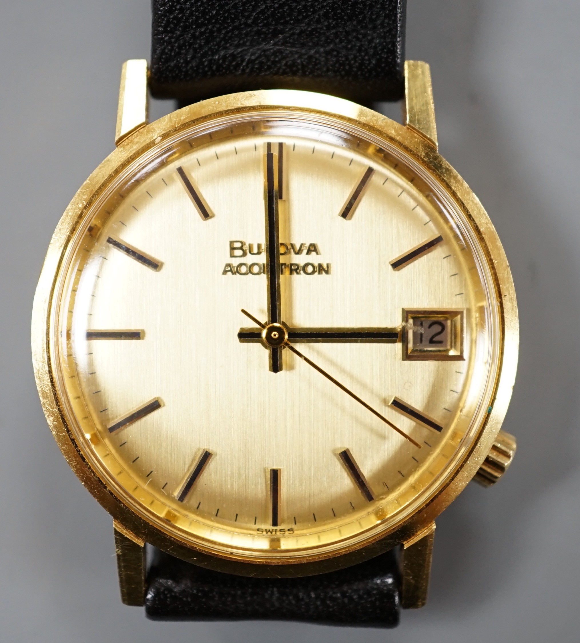 A gentleman's 750 yellow metal Bulova Accutron wrist watch, on a black leather strap, case diameter 34mm, gross weight 42.2 grams.